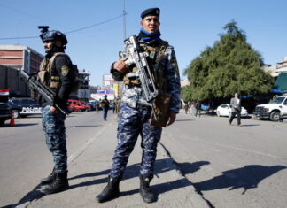 Dos policias iraquies posan en el sitio donde tuvo lugar el doble atentado suicida Foto REUTERS Thaier al Sudani